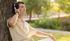 joyful-young-caucasian-man-listening-music-park