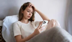 medium-shot-anxious-woman-laying-bed-with-smartphone_11zon
