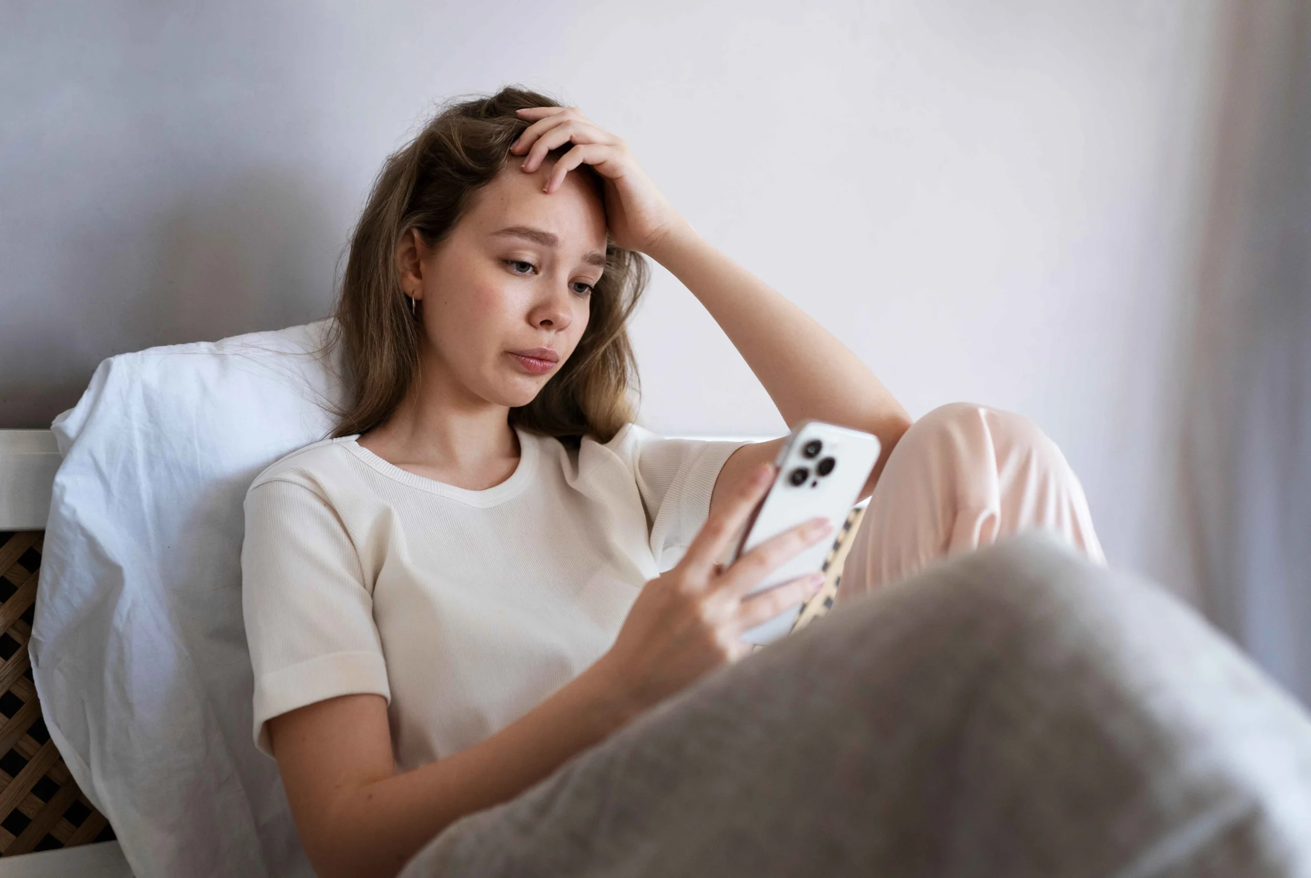 medium-shot-anxious-woman-laying-bed-with-smartphone_11zon